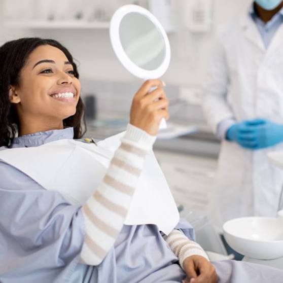 Happy dental patient holding hand mirror